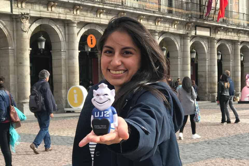 马德里的一名女学生手拿着软绵绵的比利肯，背景是拱门