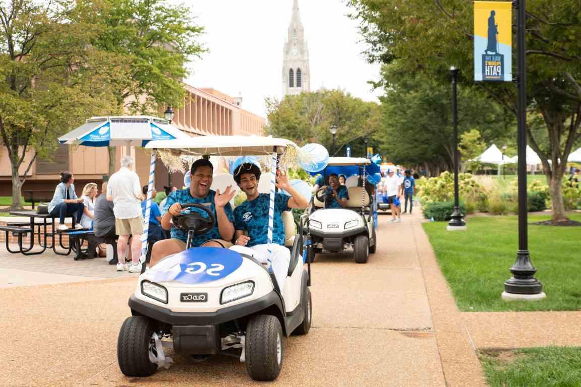 学生自治会的高尔夫球车开过校园，背景是大学教堂