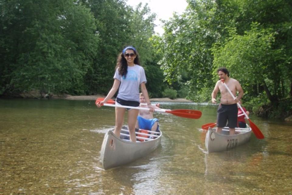 学生们在清澈的河水和岩石底部划着独木舟.
