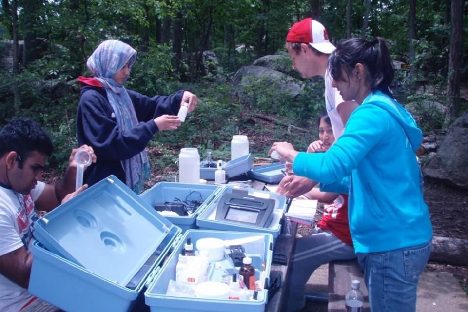 学生们站在野餐桌旁，用生物设备检测样本.