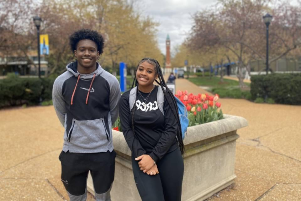 Two high school students pose for a photo on West Pine Mall, with the clock tower in the background.