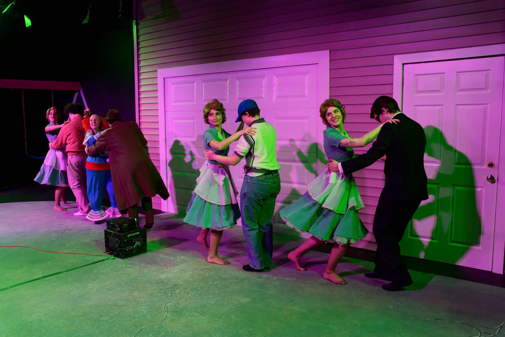 一群人在紫色和绿色的背景下成双成对地跳舞