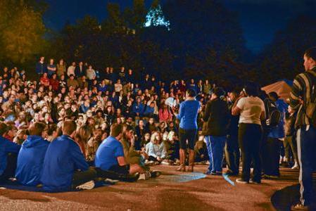 晚上，学生们聚集在钟楼周围，一位演讲者站在麦克风前.