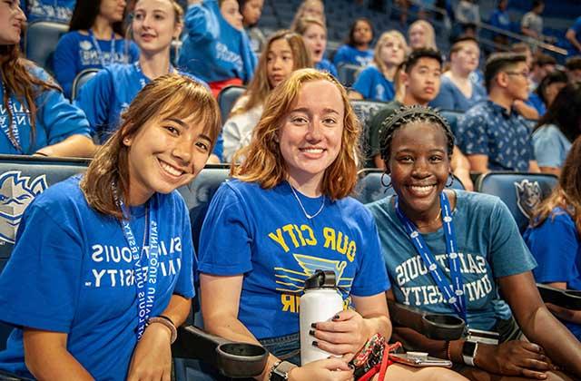 Three new freshman students sitting in the stands at Chaifetz Arena at convocation