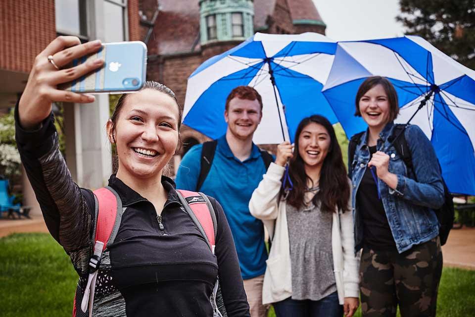 学生们在博彩网址大全的蓝色雨伞下自拍