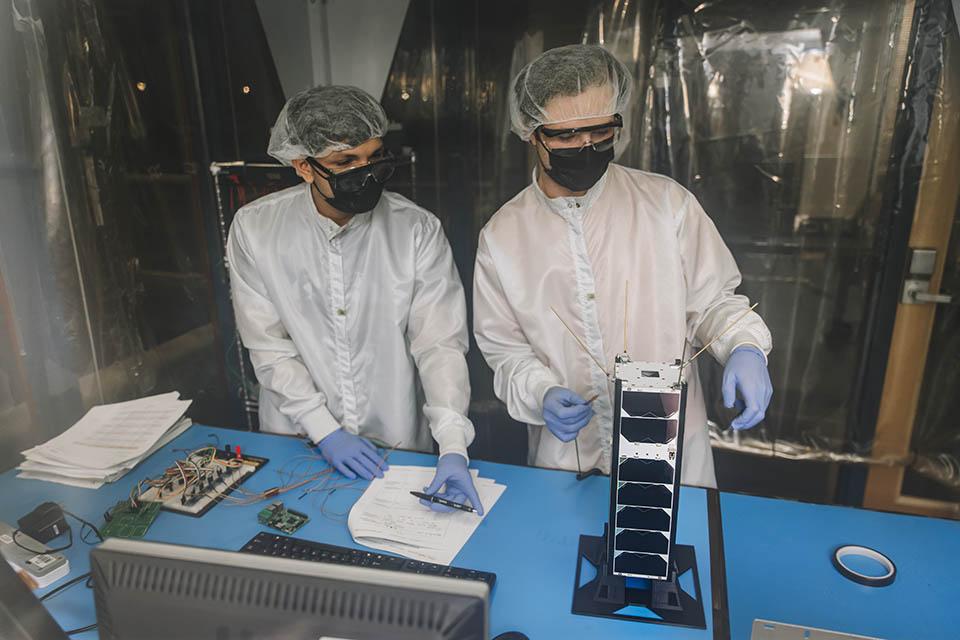 两个学生在科学工作台上研究一个小卫星.