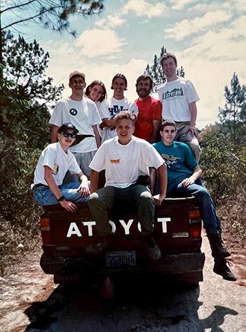 A group of eight teen boys stand and sit in the bed of a Toyota pickup truck.