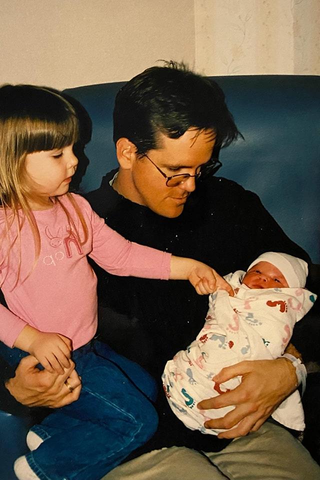 索威尔抱着刚出生的女儿，大女儿坐在他的腿上